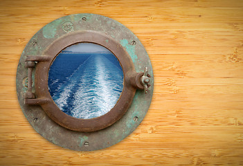 Image showing Antique Porthole on Bamboo Wall with View of Ship Ocean Trail