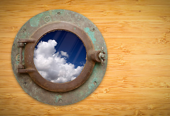 Image showing Antique Porthole on Bamboo Wall with View of Blue Sky and Clouds