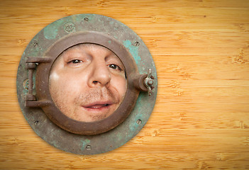 Image showing Antique Porthole on Bamboo Wall with Funky Man Looking Through