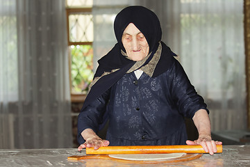 Image showing Senior woman rolling out dough
