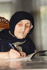 Image showing Elderly woman writing at table