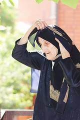 Image showing Elderly woman adjusting headscarf