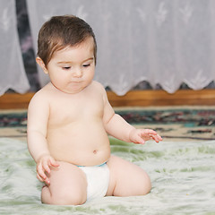 Image showing Baby sitting on green carpet