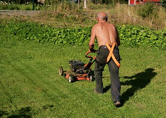 Image showing Senior mowing a lawn