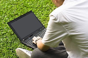 Image showing Man siting on the grass using laptop 