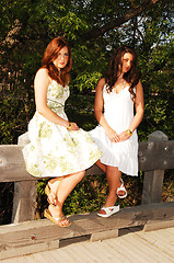 Image showing Two sisters sitting on bridge.