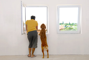 Image showing Man and dog looking through window