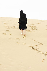 Image showing Woman walking up sand hill