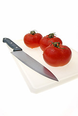 Image showing Cutting white plastic board with a knife and tomato