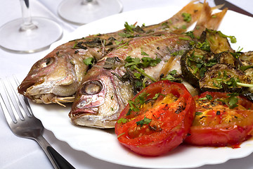 Image showing Two Grilled fish with vegetables and herbs on the dish