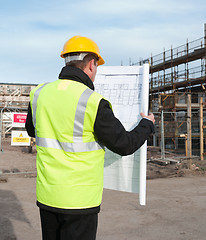 Image showing Rear view of architect looking down at plans