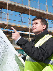 Image showing Builder points up at construction site