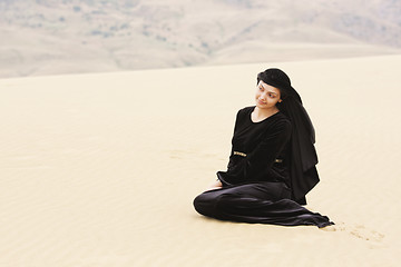 Image showing Woman in black sitting on sand