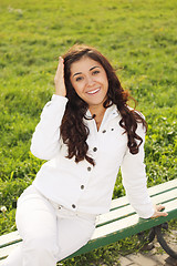 Image showing Young smiling brunette sitting on bench