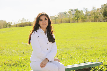 Image showing Young brunette sitting on bench