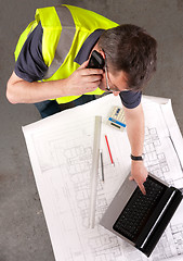 Image showing Builder phones about construction blueprint