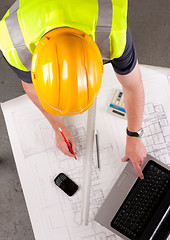 Image showing Builder inspects construction plans.