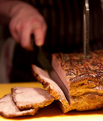 Image showing Chef slices roast pork