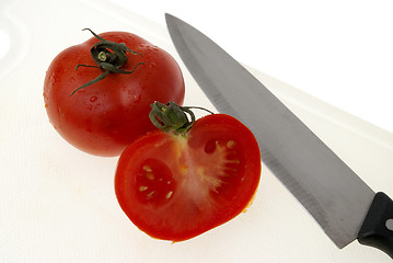 Image showing Cutting white plastic board with a knife and tomato