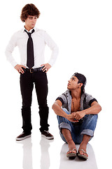 Image showing two men of different ethnicity, one sitting looking at the other standing