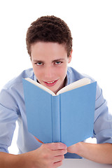 Image showing cute boy reading a book on his desk