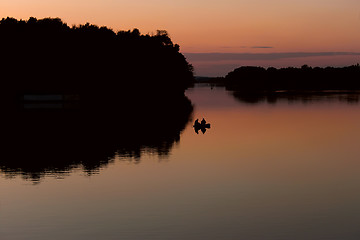 Image showing Fishermen on a boat floating on the lake after sunset