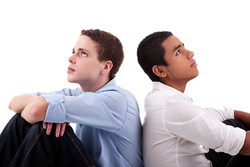 Image showing two young man of different colors, sitting on floor, back to back