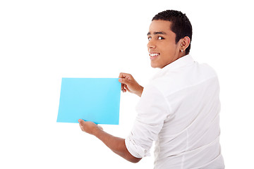 Image showing young latin man, from back, with blue  card in hand, smiling