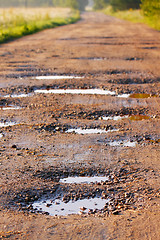 Image showing Red clay road with holes