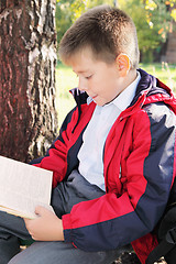 Image showing Kid reading book in park sideview