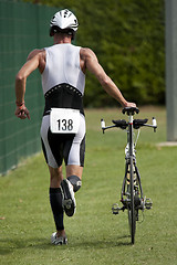 Image showing Triathlete pushing his bike