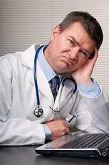 Image showing Bored doctor sits at laptop