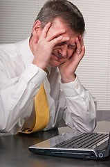 Image showing Anxious business man holds head to reduce headache