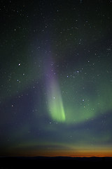 Image showing Green-purple streak of aurora over twilight horizon. Many stars