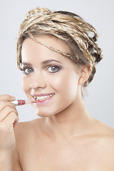 Image showing Portrait of beautiful young woman applying lipstick.