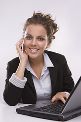 Image showing woman using a laptop computer and talking on the phone