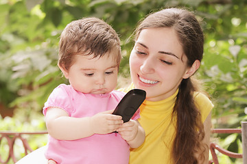 Image showing Baby girl looking at phone receiver