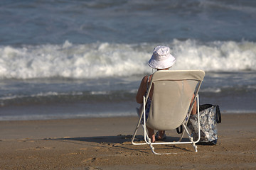 Image showing old lady sitting in a chair on the beach