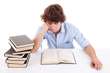 Image showing cute boy studying and reading a book on his desk