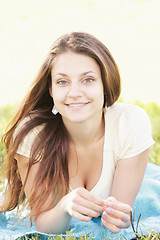 Image showing Smiling brunette laying down on blue towel