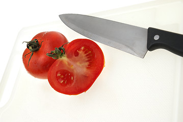 Image showing Cutting white plastic board with a knife and tomato