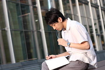 Image showing casual asian businessman texting on his book