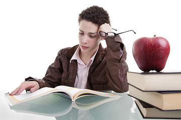 Image showing cute boy studying and thinking, along with one on apple top of some books