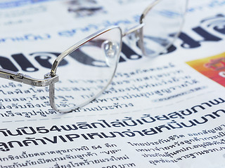 Image showing Close-up of Thai language newspaper and a pair of glasses