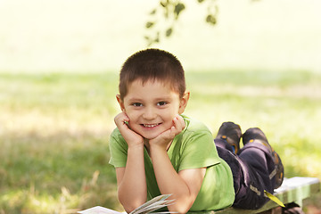 Image showing Little smiling kid with book in park