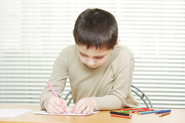 Image showing Cute boy at desk drawing with crayons