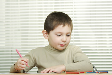 Image showing Cute boy at desk with crayons