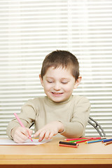 Image showing Smiling boy drawing with crayon