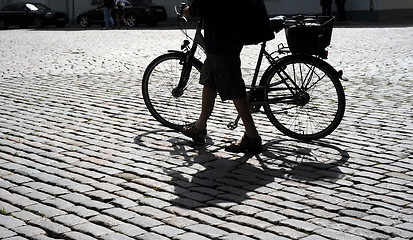 Image showing Man walking his bicycle