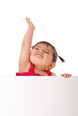 Image showing Happy baby holding white board and reaching up